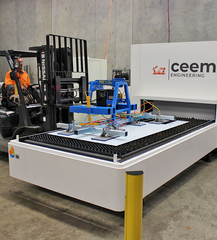 Ceem Engineering team member placing a large sheet of metal into laser cutter
